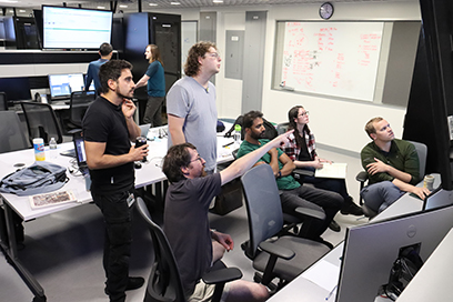 Six participants of the 20th Exotic Beam Summer School (EBSS 2023) look at computer monitors while conducting an experiment.