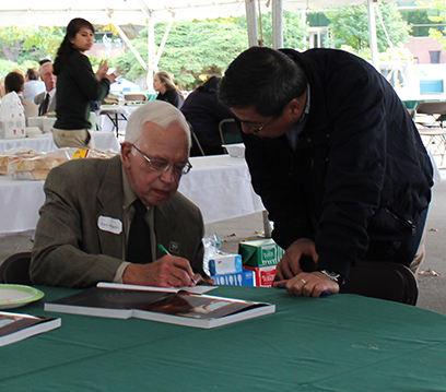 Sam Austin, Laboratory Director Emeritus, (seated) signs a copy of his book, "Up From Nothing: The Michigan State University Cyclotron Laboratory."