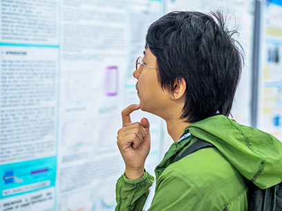 A graduate student reads over results at a poster session.