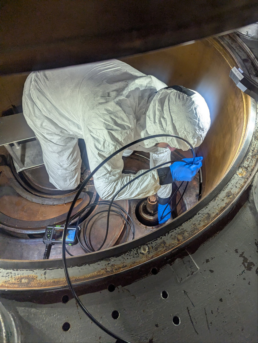 An FRIB engineer works in the beam chamber of the K500 cyclotron