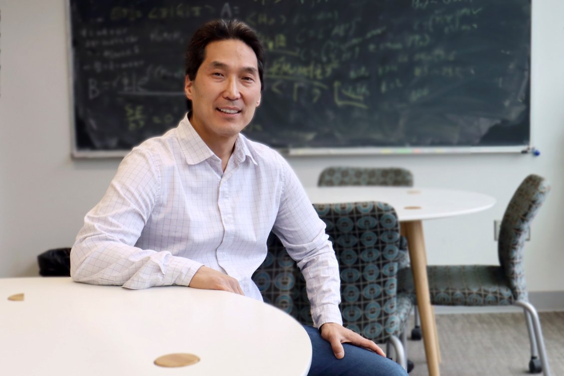 Photo of Dean Lee sitting at a desk in a classroom setting