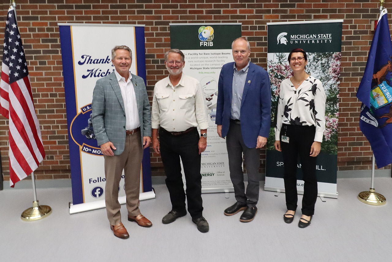 Photo of people standing in front of brick wall. From left: Michigan State University President Kevin Guskiewicz, U.S. Senator Gary Peters, FRIB Laboratory Director Thomas Glasmacher, and FRIB/MSU Professor of Physics Artemis Spyrou.
