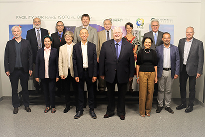 Visitors from the French National Centre for Scientific Research (CNRS) and the Office of Nuclear Physics in the U.S. Department of Energy Office of Science pose for a group photo in front of an FRIB photo mural.