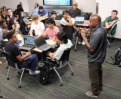 Participants of the Physicists Inspiring the Next Generation: Exploring the Nuclear Matter (PING) program listen during a classroom lesson from Paul Gueye (bottom right), associate professor of physics at FRIB and in MSU’s Department of Physics and Astronomy.