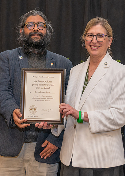 Jaideep Taggart Singh (second from left), receives his Donald F. Koch Quality in Undergraduate Teaching Award from MSU Interim President Teresa Woodruff (second from right). Photo credit: Derrick Turner, University Communications.