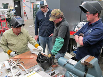 Joseph Brock from JLab demonstrates titanium welding techniques while Ian Sprague, Jason VanAken, and Jim Brownlee observe.