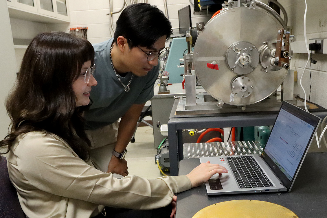 Undergraduate students analyzing research on a computer
